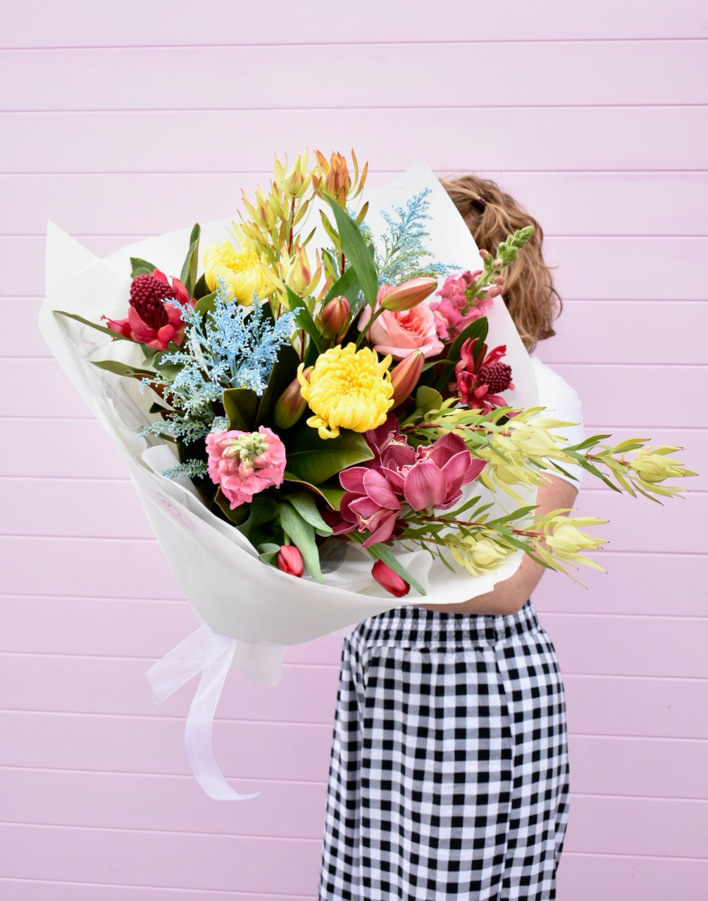 Florist holding a bright fresh flower bouquet. Blue, pink, red and yellow with roses, chrysanthemums and orchids