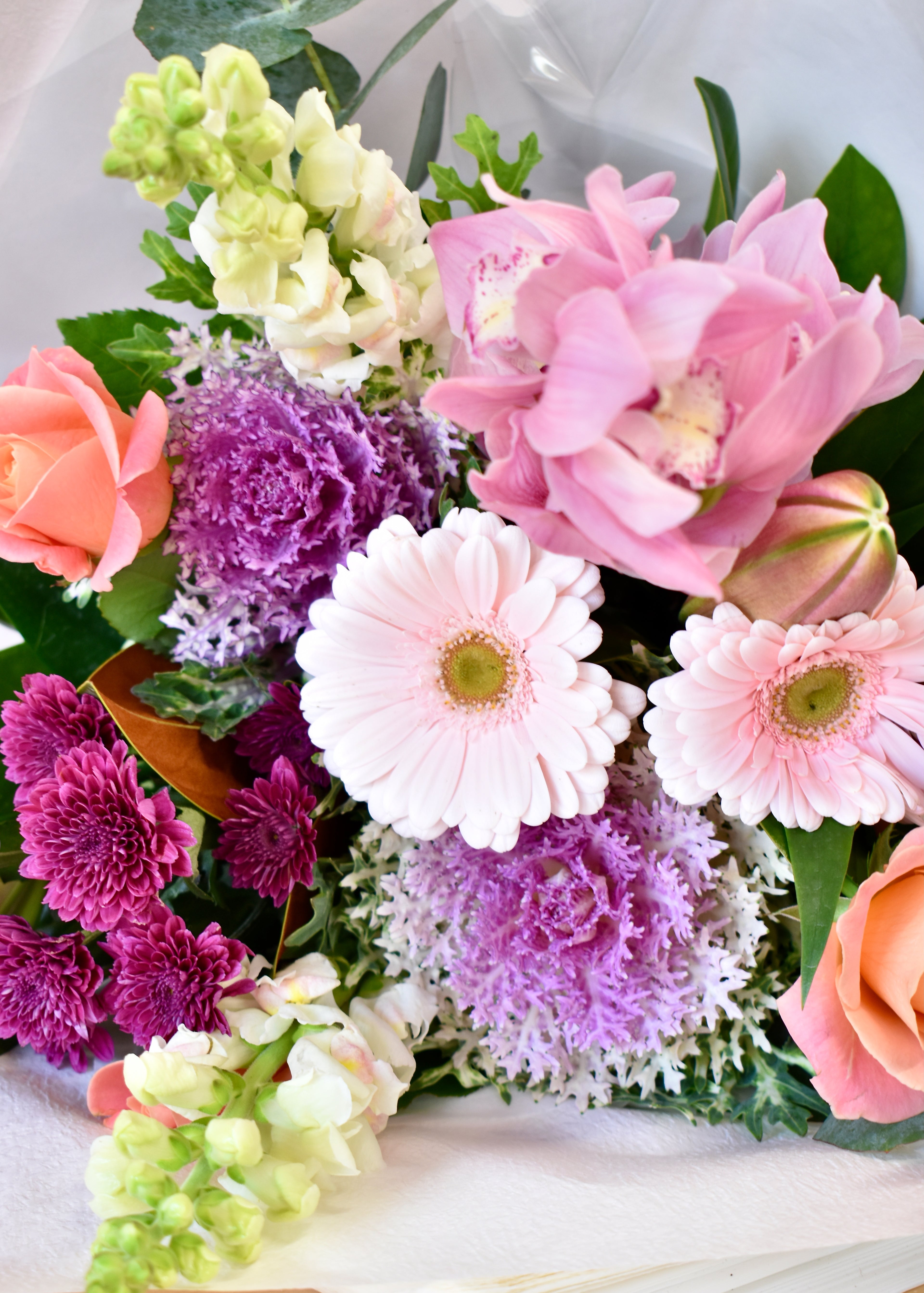 Fresh flower bouquet made with pale pink, purple and peach flowers. Featuring gerberas, roses, chrysanthemums and orchids.