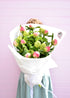 A florist holding a big bunch of coral charm peony roses, gift wrapped in white paper with Pepperberry Florist logo